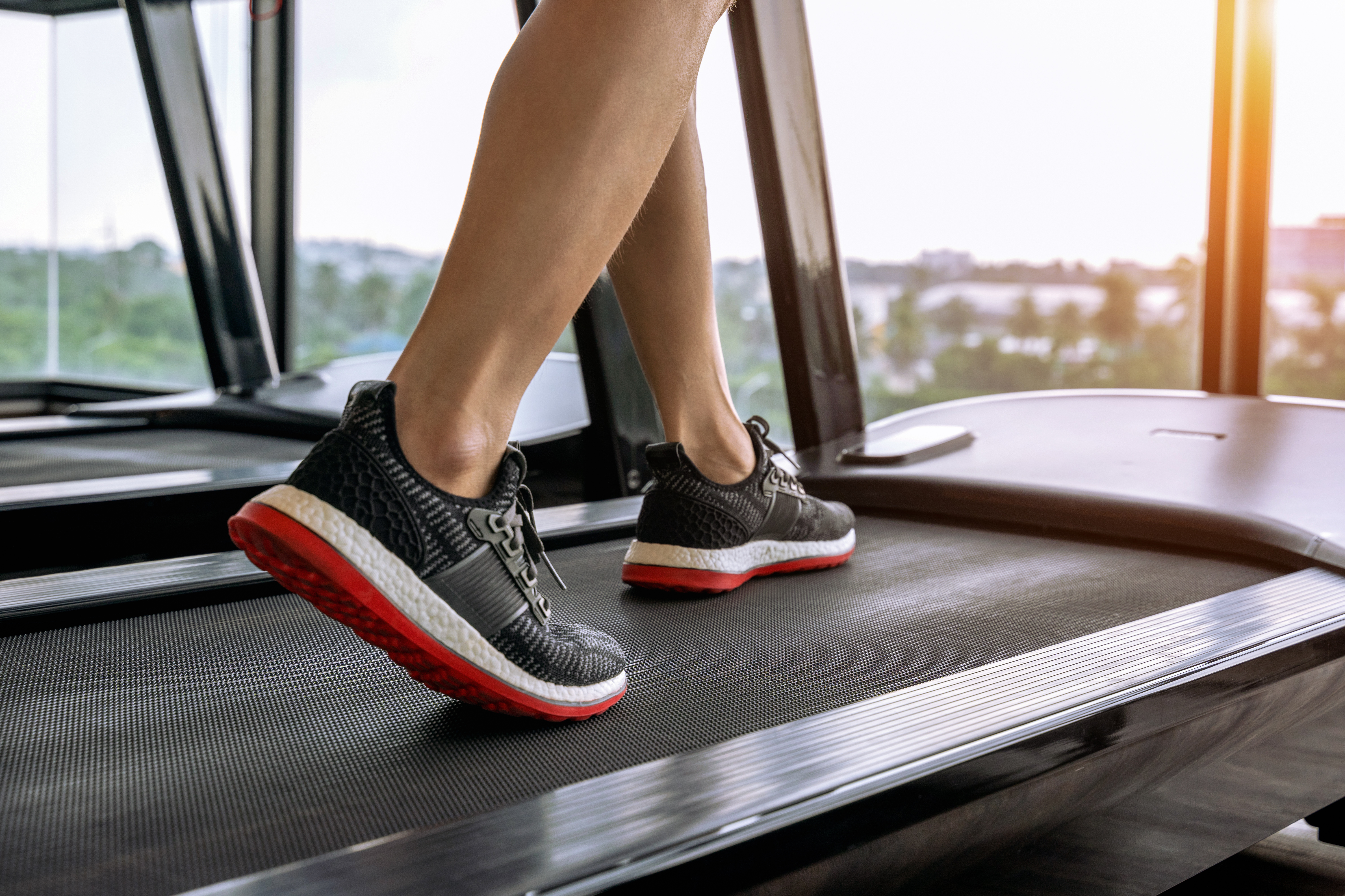 Male feet in sneakers running on the treadmill at the gym. Exerc